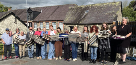 Adults standing outside buildings holding their weaved articles.