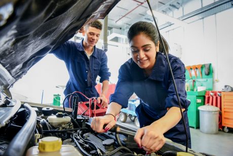 Female and Male repairing car engine.