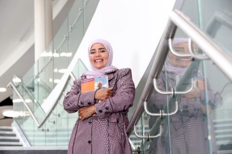 Fatma Al Nahdy standing on stairs holding her books