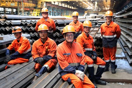 Celsa Steel staff sitting on steel girders in factory.
