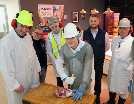 Keepak trainee butcher cutting a joint of meat with Keepak Manager and staff standing in the background