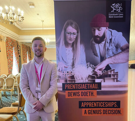 Mitchell standing by a Apprenticeships banner