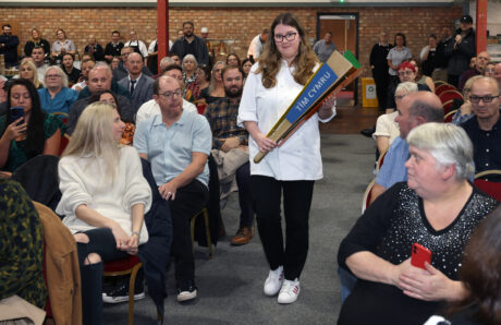 Mia Haf Rees carrying the Team Wales Skills Torch though the audience at the apprenticeship graduation ceremony.