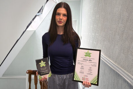 Jasmine holding her trophy and certificate.